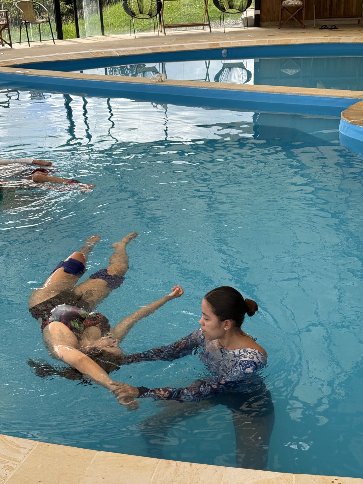 Oriana guiando a una persona que flota en la piscina